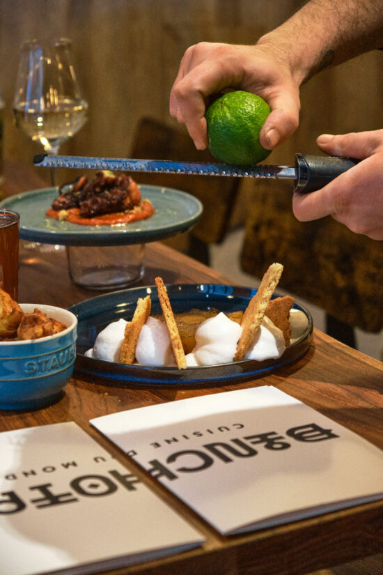 Plats et boissons servis au Binchotan, montrant une main pressant un citron vert sur des tapas.